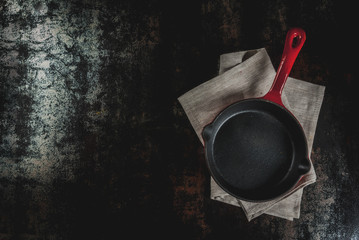 Dark rusty culinary background with empty black pan, top view copy space