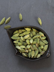 cardamom in bowl on grey stone background