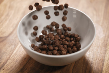 chocolate cereal balls fall in white bowl for breakfast