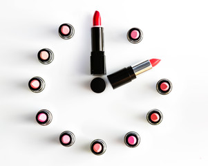 clock face and arrows on white background made from lipsticks