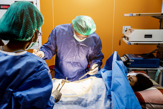 doctor and assistance Medical team performing surgery on a patient with focus and stressful moment in operation room in hospital or clinic health concept
