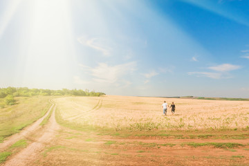 Obraz premium Young man and woman running on the yellow field in the sunlight