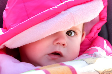 Portrait niedliches Baby Mädchen guckt erschrocken unter großer Kapuze hervor