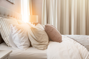 Bed maid-up with clean white pillows and bed sheets in beauty room. Close-up. Lens flair in sunlight.