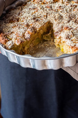Man Chef Holding Baking Form with Homemade Vegan Eggless Apple Cake with Crumbles Cut out Slice. Natural Light Authentic Cozy Atmosphere. Fall Autumn Thanksgiving. Kinfolk Hygge