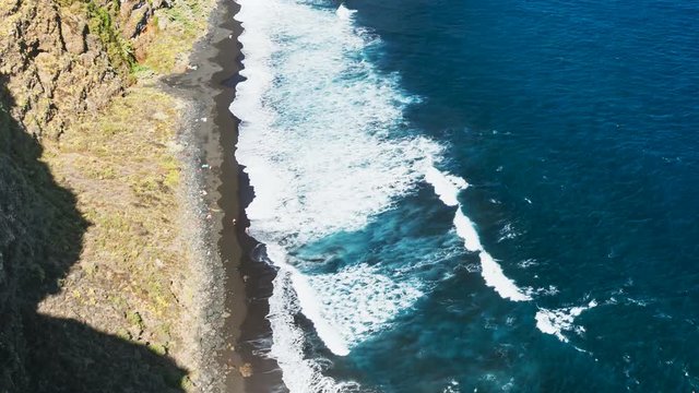Timelapse sequence of tall waves at Playa de Nogales beach in La Palma, Spain. High angle view  from an observation point on the cliff with some tourists running around.