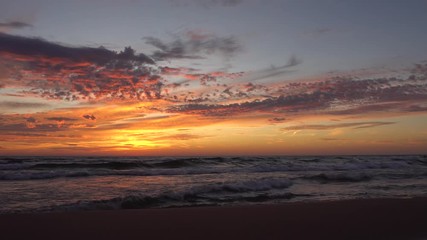 Waves washing ashore with sunset over lake - beautiful clouds in the sky and reflection of sunset on water
