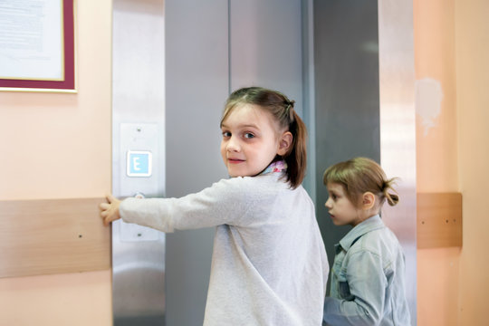 two girls near   elevator clicking on  call button