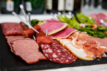 Food tray with delicious salami, pieces of sliced ham, sausage, salad - Meat platter with selection