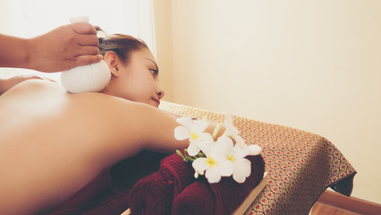 Obraz na płótnie Canvas Selected focus on a massager's hand, taking massage on beautiful women, using herbal compress, women laying down on the bed. Thai massage. Massage is for relaxation and muscle pain relief.