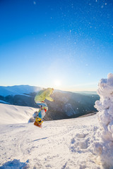 Snowboarding. A man is jumping. Mountain range on the background.