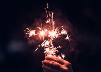 Hand holding burning Sparkler blast on a black background at night,holiday celebration event...