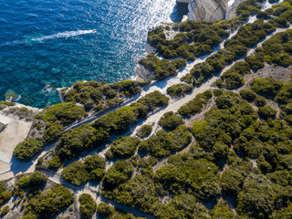 Vista aerea sulle scogliere di calcare bianco, falesie. Barche in navigazione con turisti. Corsica, Francia. Stretto delle Bocche di Bonifacio che la separa la Corsica dalla Sardegna