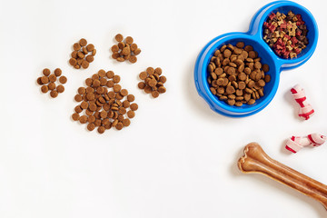 Dry pet food in bowl and bone on white background top view