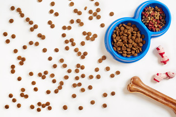 Dry pet food in bowl and bone on white background top view