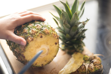 Hands of a girl are cutting pineapple a wooden board background - 181352740