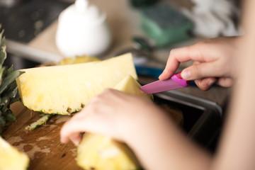 Woman's hands cutting pineapple