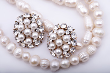 Pearl necklace and pearl earrings on a white background.