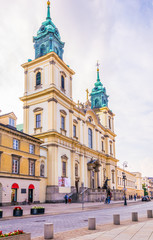 People are strolling through the nowy swiat street in front of the Church of the Holy Cross, Warsaw, Poland