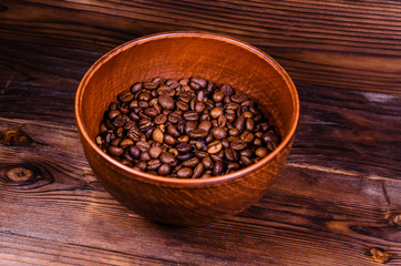 Roasted coffee beans in bowl on wooden table