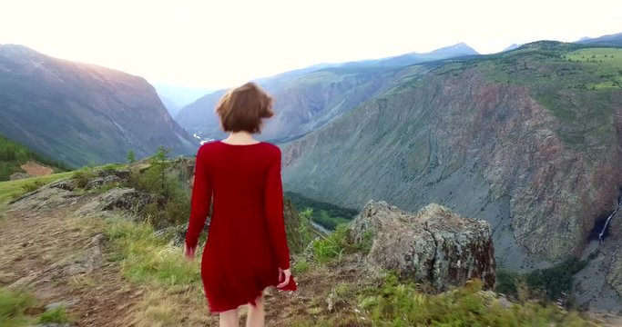Elegant young lady in a red dress on a mountain