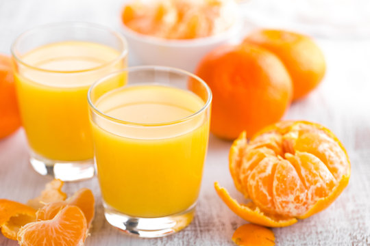 Tangerines, peeled tangerines and tangerine juice in glass. Mandarine juice.