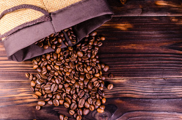 Roasted coffee beans in sack on wooden table. Top view