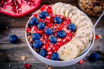 Homemade granola with banana, pomegranate, blueberries, chia seeds, quinoa and coconut