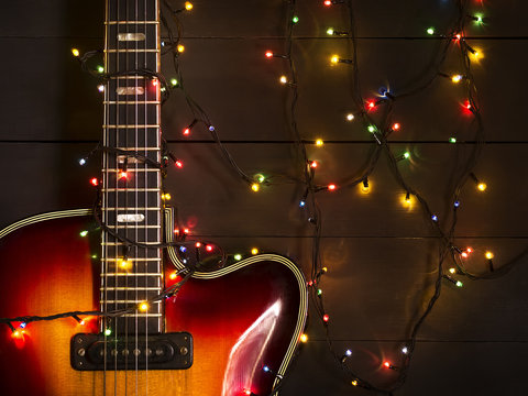 Old electric guitar with a lighted garland on a dark background. Greeting, Christmas, New Year greeting card. Copy space.