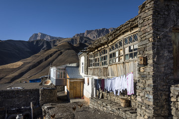 Obraz na płótnie Canvas Azerbaijan, Greater Caucasus, Khinalug ( Xinaliq ): Clothesline rope and old house in small town with beautiful mountains in the north of Azerbaijan near Quba with clear blue sky in the background.
