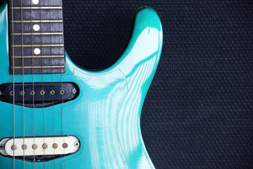 close up of guitar fingerboard with guitar amplifier background.