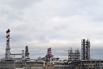 general view of a chemical or oil refinery with a multitude of pipelines, factory pipes and distillation columns under a cloudy sky