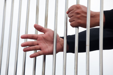 hand of prisoner in jail with white background.