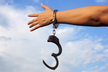 hand in handcuff against blue sky