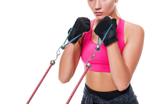 Strong Woman Using A Resistance Band In Her Exercise Routine. Young Woman Performs Fitness Exercises On White Background. Close Up