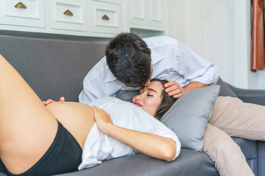 Handsome man kiss beautiful pregnant woman at living room. concept of pregnancy, family and lover relation.