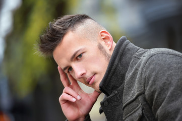 young man thinking while sitting on a bench in autumn