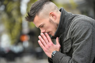 young sad man thinking while sitting on a bench in autumn