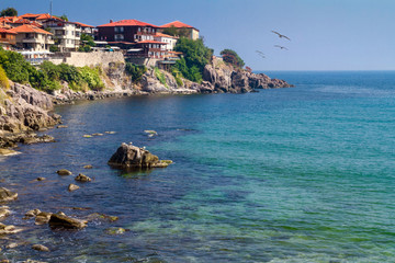 Fototapeta na wymiar Coastal landscape - the rocky seashore with houses the sunny day, town of Sozopol on the Black Sea coast in Bulgaria