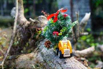 Miniature of lorry transportation toy with Christmas tree in blurred nature background. Holidays concept.