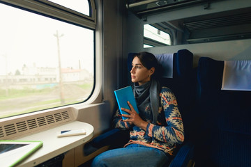 Pretty woman traveling by train sitting near window. Enjoying travel