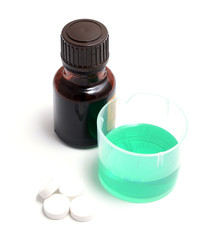 green medical liquid in a plastic cup with bottle