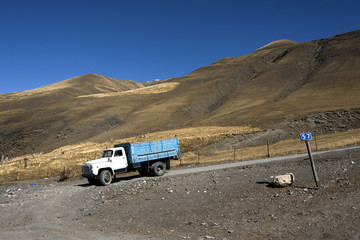 Azerbaijan, Greater Caucasus, Khinalug ( Xinaliq ): Street scene with old Russian truck in the rural north of Azerbaijan near Quba and beautiful high mountains in the background.