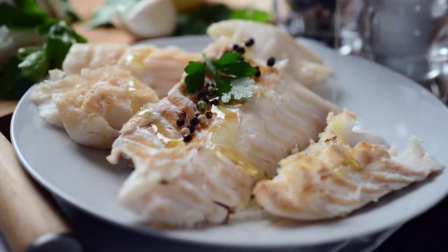 Pouring olive oil on raw cod fillet