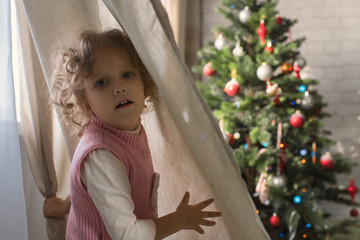 Girl playing in the room with a Christmas tree