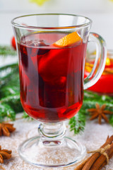 New Year's mulled wine in a glass on the background of twigs, candles and garlands.
