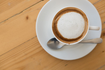 hot cappuccino coffee in white cup on wood table