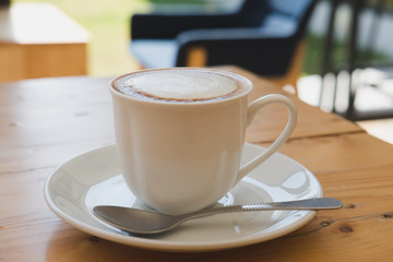 Cup of cappuccino coffee, hot mocha drink with cream on wood table