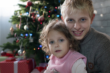 Girl and boy playing in the room with a Christmas tree