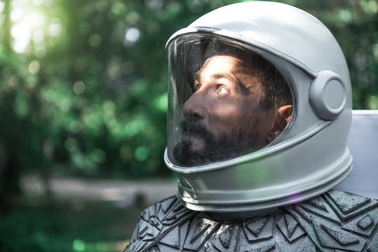 Surprised spaceman wearing helmet is looking at sunbeam with shock. Profile. Copy space on left side